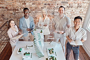 Group of diverse architects discussing plans, blueprints and schematics during a meeting in their office boardroom