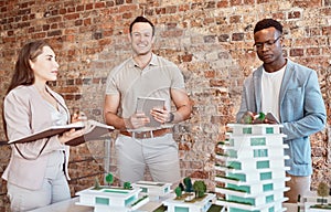 Group of diverse architects discussing plans, blueprints and schematics during a meeting in their office boardroom