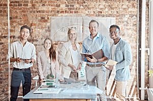 Group of diverse architects discussing plans, blueprints and schematics during a meeting in their office boardroom