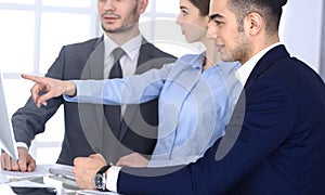 Group of diverse business people discussing questions at meeting in modern office. Colleagues working with computer at