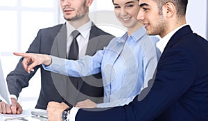 Group of diverse business people discussing questions at meeting in modern office. Colleagues working with computer at