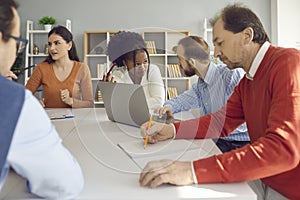 Group of diverse business people discussing their projects sitting at office table together