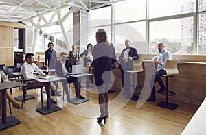 Group of diverse business people listen to speech by female speaker at business meeting.