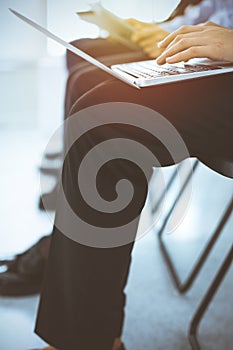 Group of diverse business people working in sunny office, close-up. Woman typing on laptop computer. Conference or