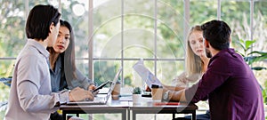 A group of diverse businesspeople, Asian and caucasian, meeting and working together in a modern office in an intimate manner.