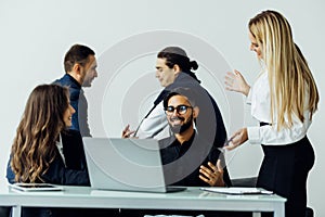 Group of diverse businesspeople going over paperwork together and working on a laptop at a table in an office