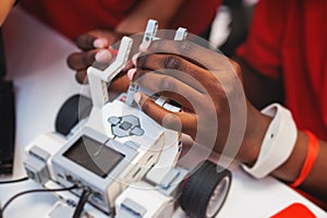 Group of diverse children kids with robotic vehicle model, close-up view on hands, science and engineering lesson in a classroom,