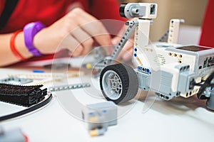 Group of diverse children kids with robotic vehicle model, close-up view on hands, science and engineering lesson in a classroom,