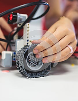 Group of diverse children kids with robotic vehicle model, close-up view on hands, science and engineering lesson in a classroom,