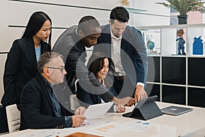 Group of diverse colleagues in formal clothes standing and sitti