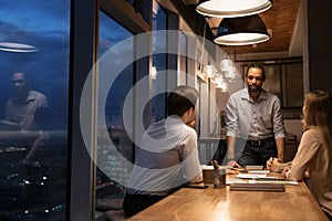 Group of diverse colleagues working until late in modern office