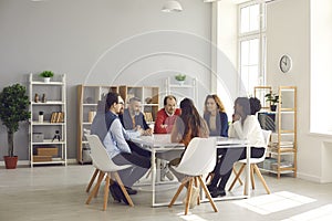 Group of diverse company employees sitting at big table in corporate office meeting