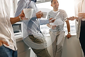 Group of diverse coworkers drink coffee during break and talking about work project