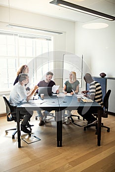 Group of diverse designers talking together around an office tab
