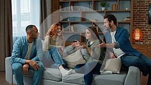 Group of diverse ethnic multiracial friends girls guys sit on sofa at home talking argue conflict friendly dispute