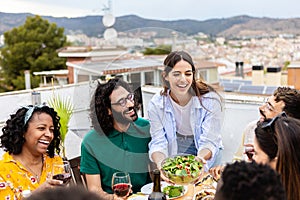 Group of diverse friends enjoying dinner eating in a terrace