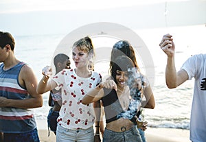 Group of diverse friends enjoying sparklers at the beach togethe