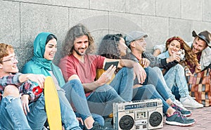 Group of diverse friends having fun outdoor - Millennial young people using mobile phones and listening music with vintage boombox