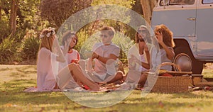 Group of diverse friends having lunch and enjoying in the park while having a picnic