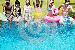 Group of diverse friends splashing water at the swimming pool