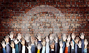 Group of Diverse Hands Raised on Brick Wall