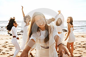 Group of diverse happy ladies having fun and dancing outdoors on the beach, celebrating bachelorette party on coastline