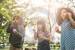 Group of Diverse Kids cute friends having bubble fun on green lawn in park.