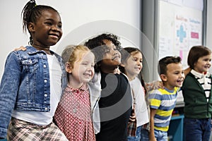 Group of diverse kindergarten students standing together in classroom photo