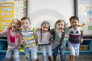 Group of diverse kindergarten students standing together in classroom