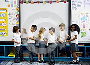 Group of diverse kindergarten students standing together in classroom