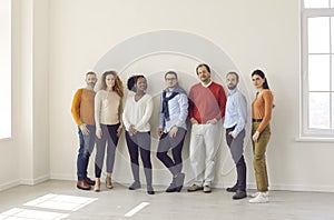 Group of diverse people in casual wear standing together in empty office or studio