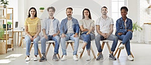 Group of diverse people sitting on chairs in row