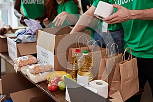Group of diverse people sort through donated food items while volunteering in community