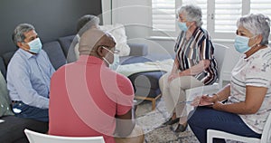 Group of diverse senior friends in face masks having support meeting