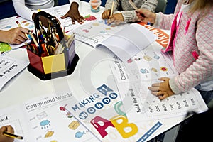 Group of diverse students coloring workbook in class