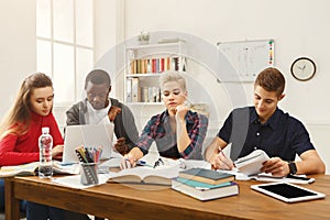 Group of diverse students studying at wooden table