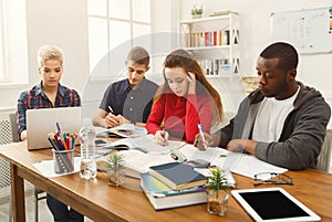Group of diverse students studying at wooden table