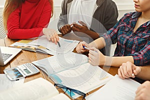 Group of diverse students studying at wooden table