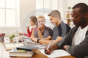 Group of diverse students studying at wooden table