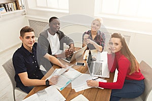 Group of diverse students studying at wooden table