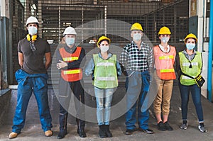 Group of diverse team of workers wearing face mask standing in front of the factory