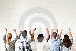 Group of Diverse Teenagers Pointing Upwards at Blank White Wall