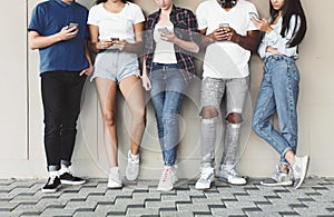 Group of diverse teenagers using cellphones outdoor