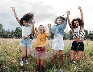 Group of diverse women jumping together outdoors. Friends having fun during vacation