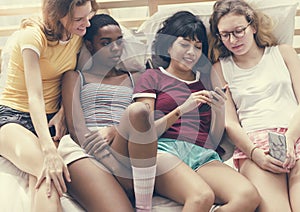 A group of diverse women lying on bed and using mobile phones