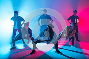 Group of diverse young hip-hop dancers in studio with special lighting effects