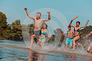 A group of diverse young people having fun together as they run along the river and play water games