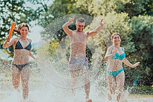 A group of diverse young people having fun together as they run along the river and play water games