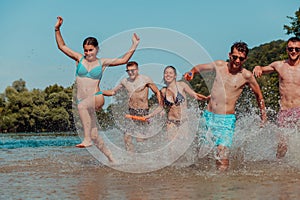 A group of diverse young people having fun together as they run along the river and play water games