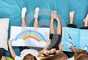 Group of Diverse Young Students Reading Children Story Book Together